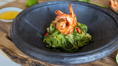 Cooked shrimp on top of zucchini noodles in a bowl with mango sauce on the side. Cooked shrimp on top of zucchini noodles in a bowl with mango sauce on the side.