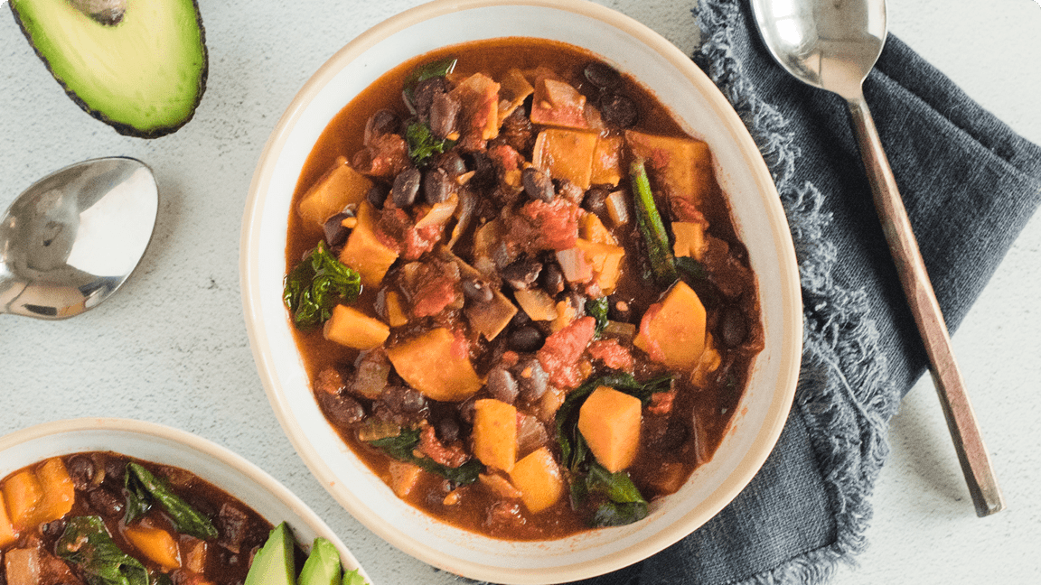 Sweet potato and black bean chilli in a bowl with garnish ready to be served.  Sweet potato and black bean chilli in a bowl with garnish ready to be served.